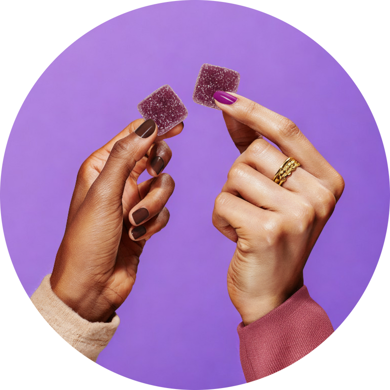 Close-up of two hands holding purple square sleep gummies showcasing sugar-coated texture against a solid purple background